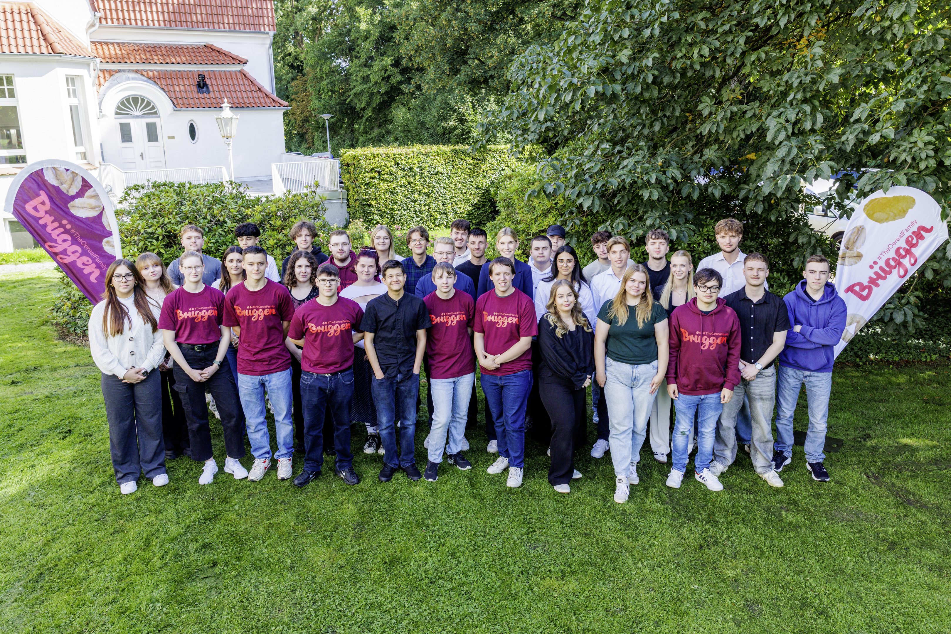 Das Bild zeigt eine Gruppe von jungen leuten, die für ein Gruppenfoto im Garten aufgestellt sind.